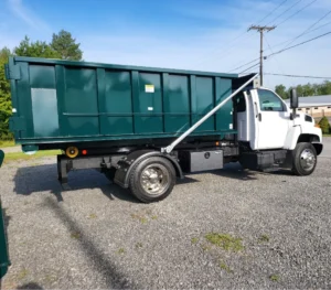 Roll-off dumpster delivery truck on a gravel lot